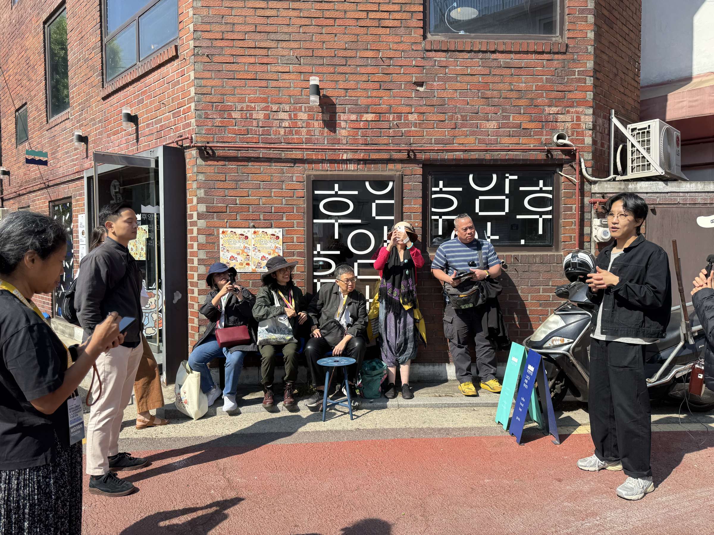 A study-tour group on a technical visit in a Korean urban-regeneration neighbourhood, led by a local host